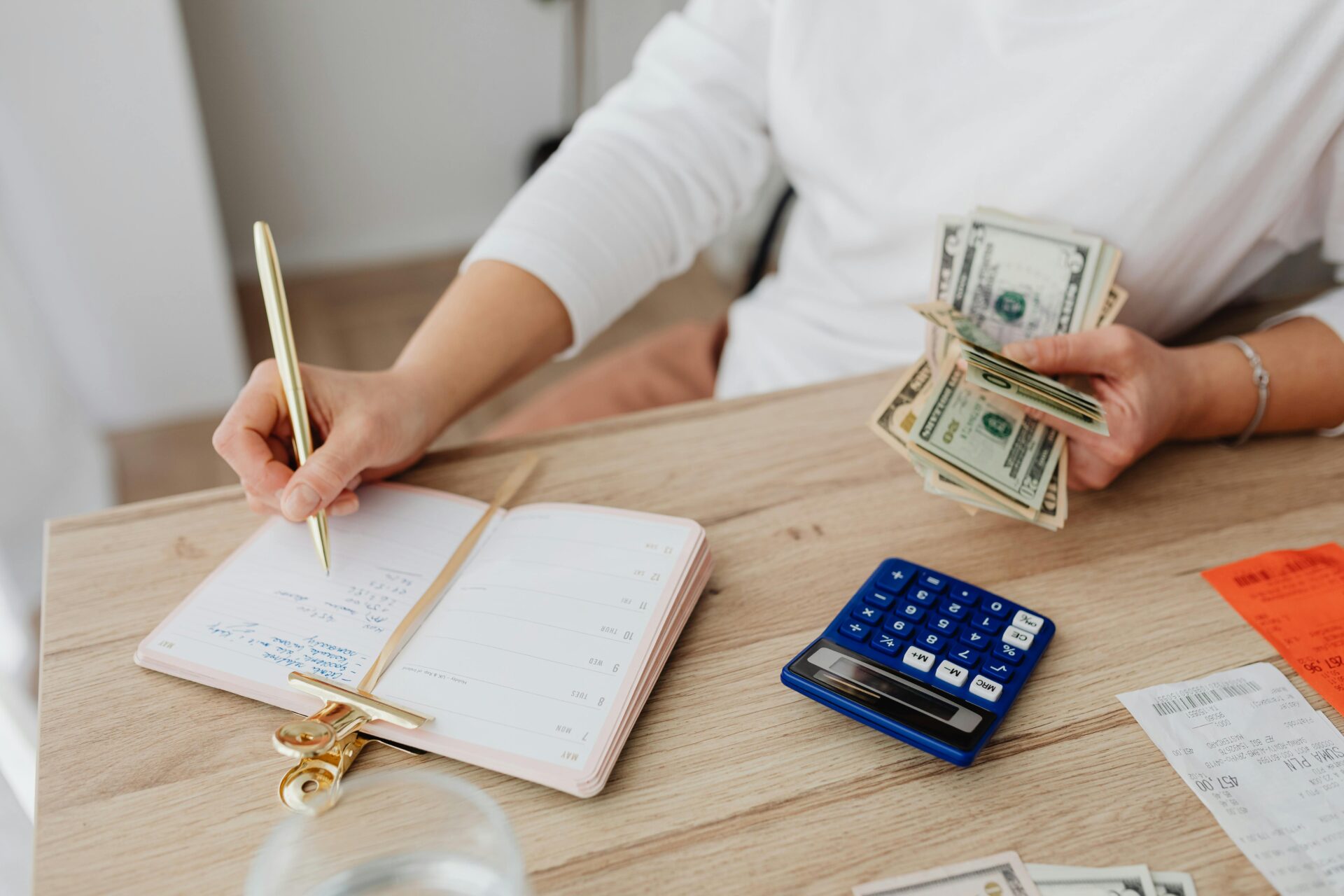 A person managing finances with cash, a notebook, and a calculator on a desk—demonstrating the need to increase credit score for SBA loan approval.